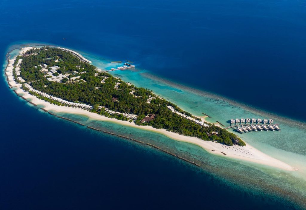 Insulă tropicală cu plaje albe și vile pe apă, văzută aerian.
