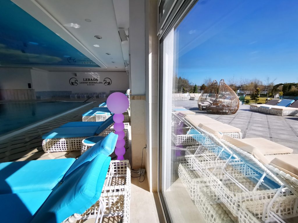 Piscină interioară și terasă exterioară văzute printr-o ușă deschisă