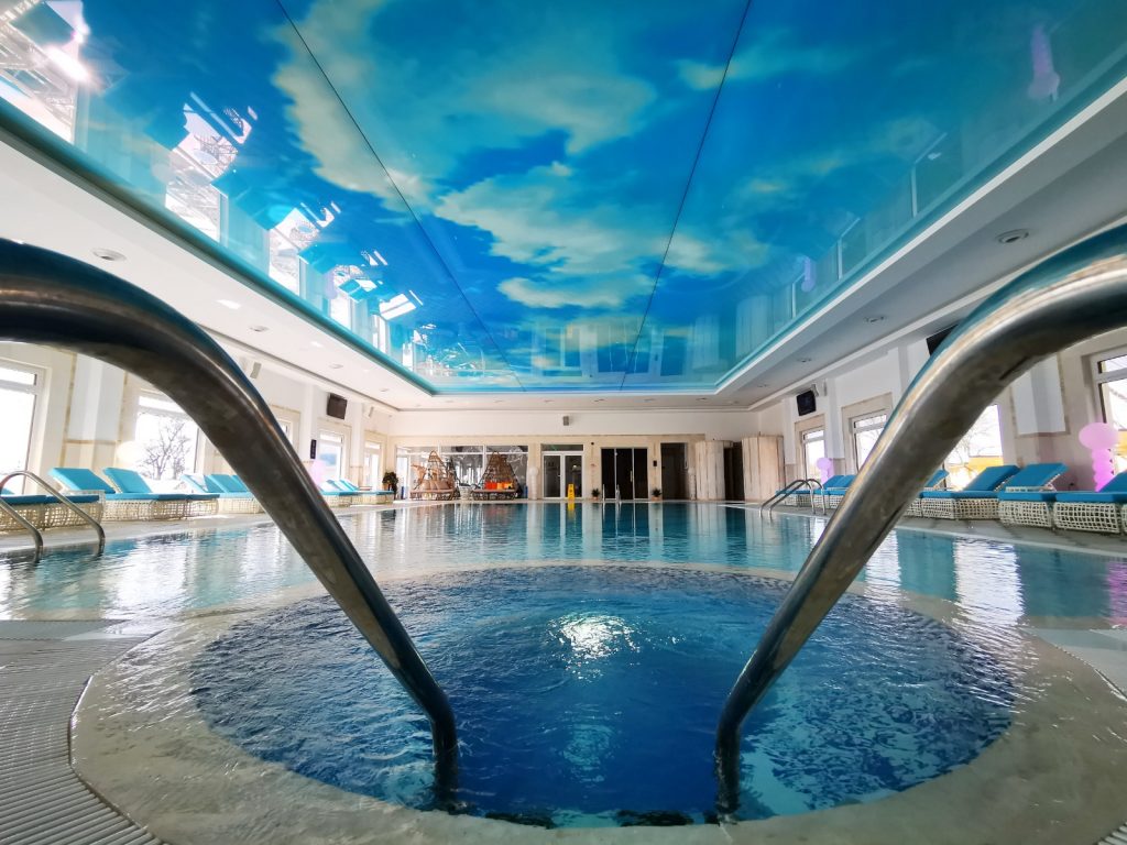 Trepte cu balustrade metalice într-o piscină interioară cu plafon pictat