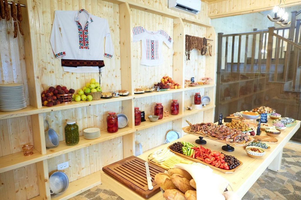 Bufet cu preparate și rafturi decorate cu borcane și cămăși tradiționale.