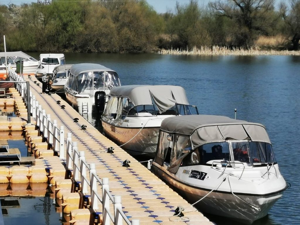 Bărci acostate în șir la un ponton de lemn.