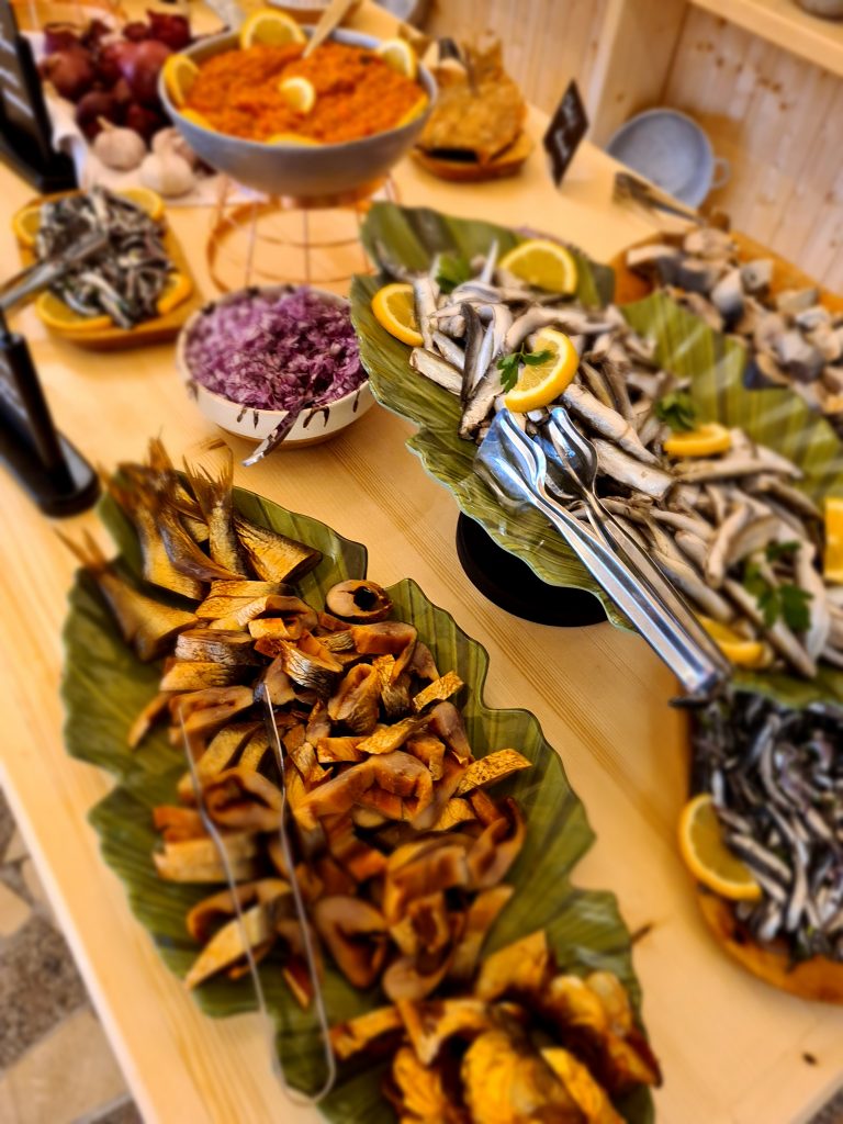 Platouri cu pești mici și legume, așezate pe o masă.