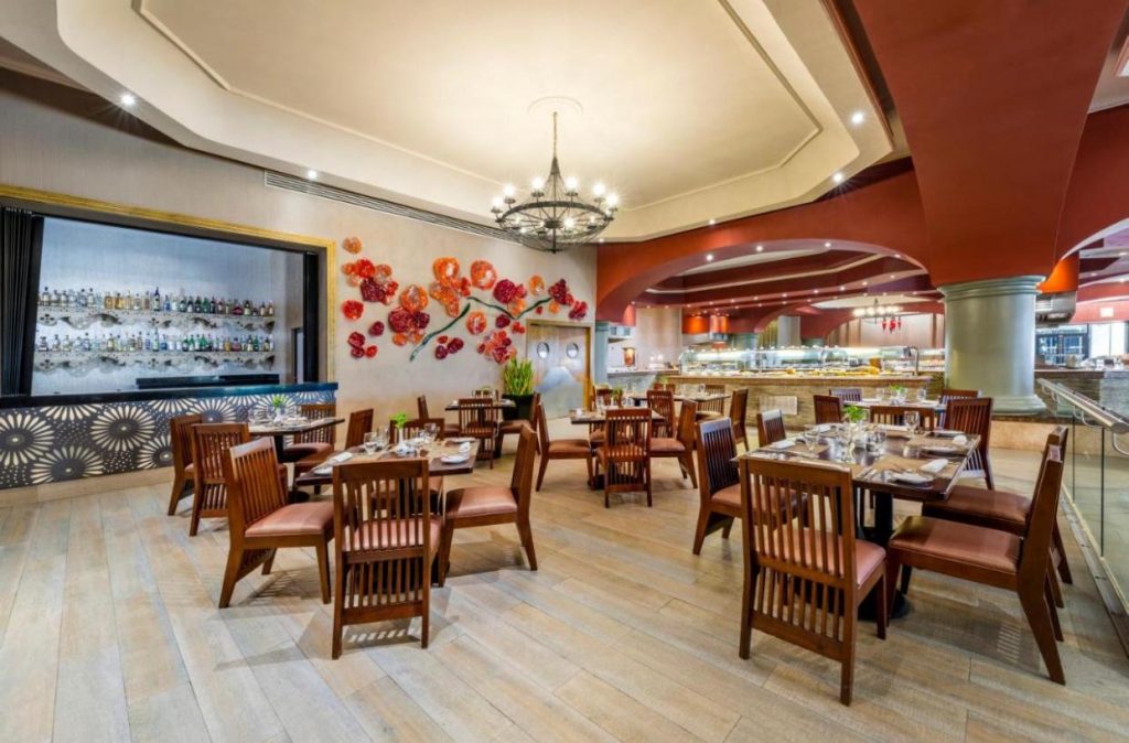 Restaurant cu mese din lemn, scaune și decor în culori calde.