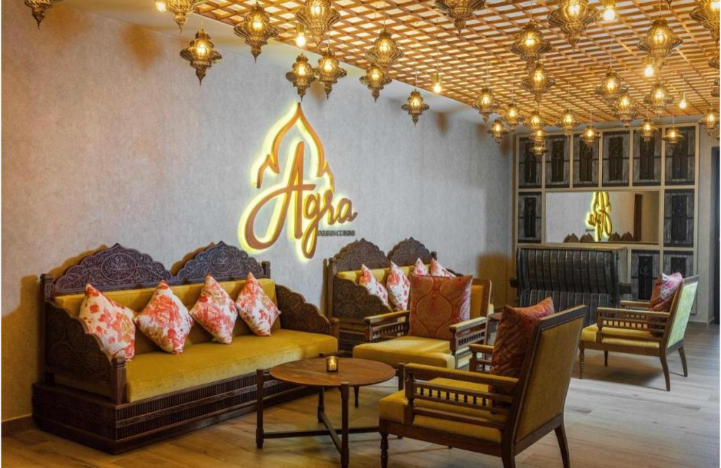 Bar cu mese, scaune și corpuri de iluminat decorative aurii.