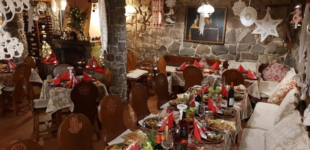 Mese festive într-o încăpere cu pereți din piatră și decorațiuni.