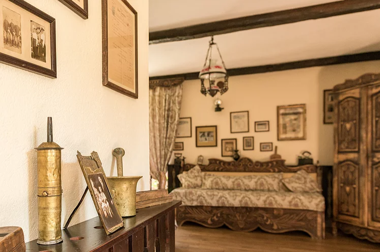 Interior rustic cu pat, dulap sculptat și obiecte decorative.