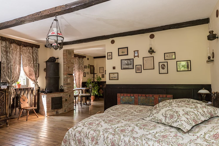 Dormitor rustic cu grinzi, pat și numeroase tablouri.