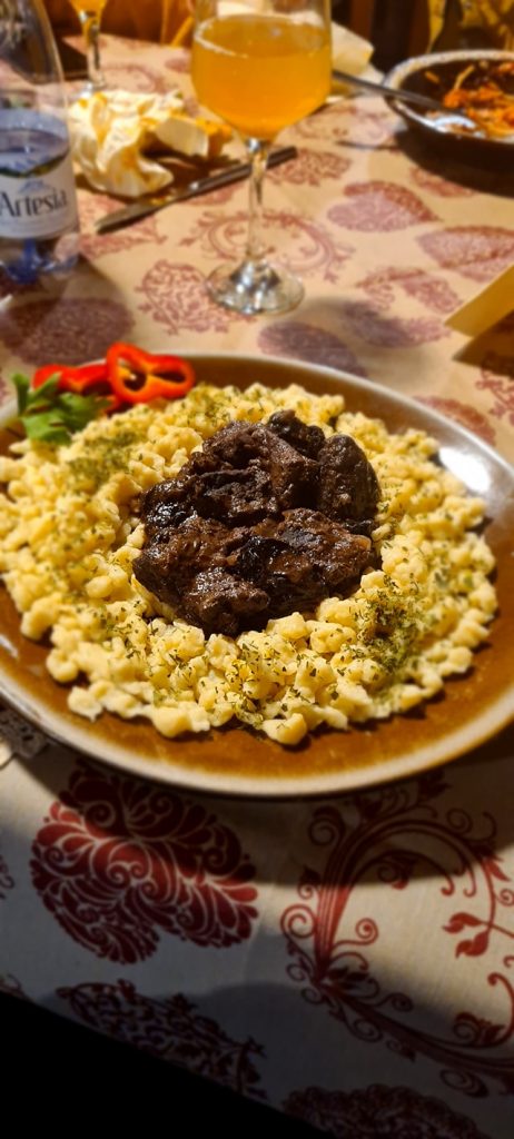 Farfurie cu paste și bucăți de carne în sos.