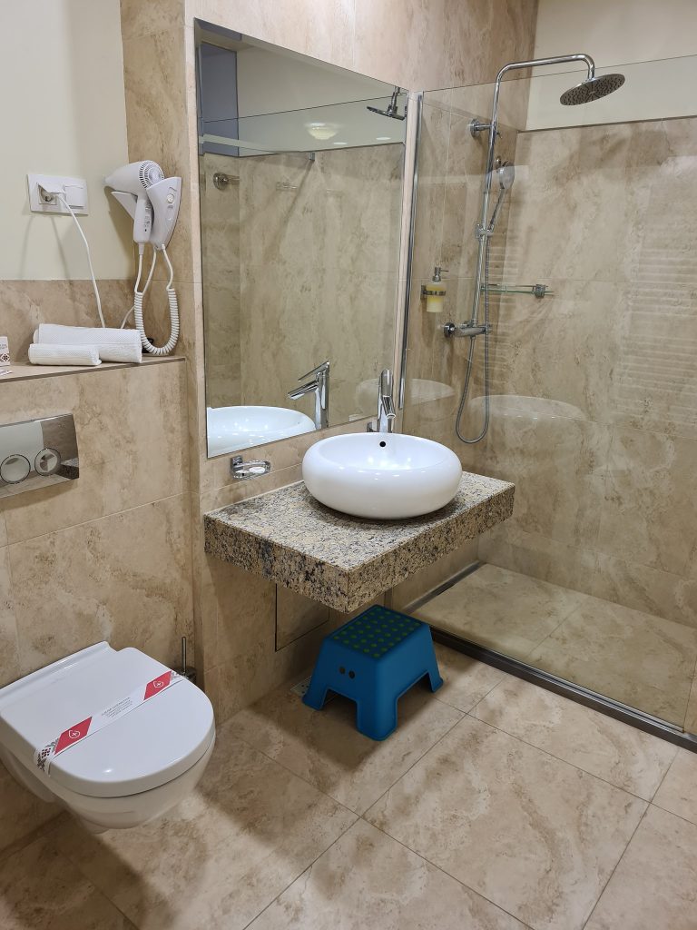 Baie cu duș din sticlă, chiuvetă și toaletă.