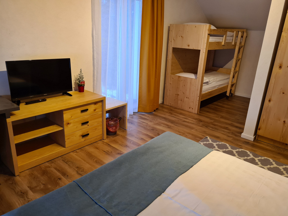 Pat suprapus din lemn și televizor într-un dormitor.