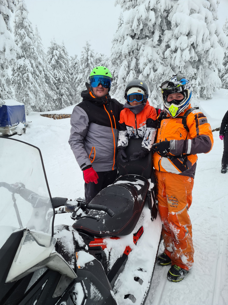 Grup cu echipament de iarnă lângă un snowmobil