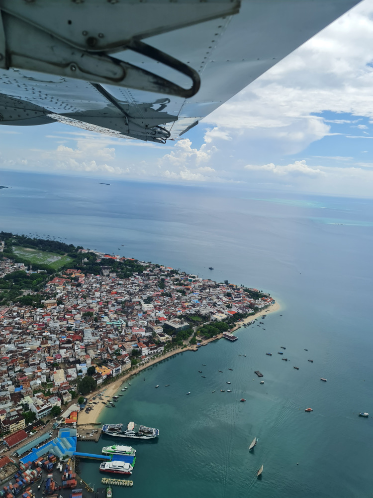 Țărm cu clădiri văzut de sus, sub aripa avionului.