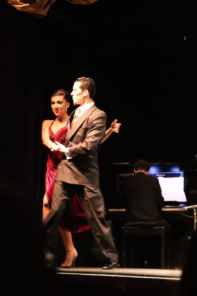 Cuplu dansând tango pe o scenă întunecată