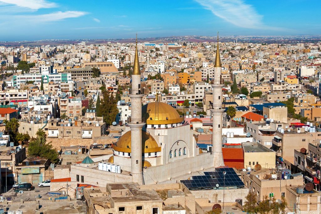 Panoramă urbană cu o moschee și două minarete.