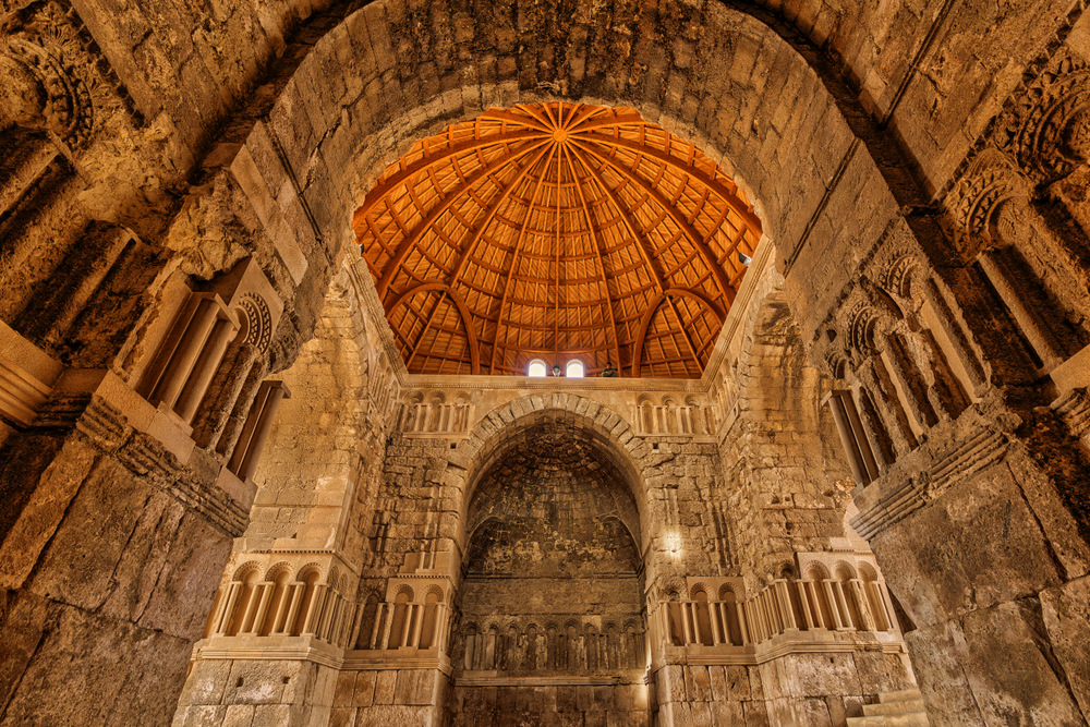 Interior monumental din piatră, cu arcade și cupolă decorată.