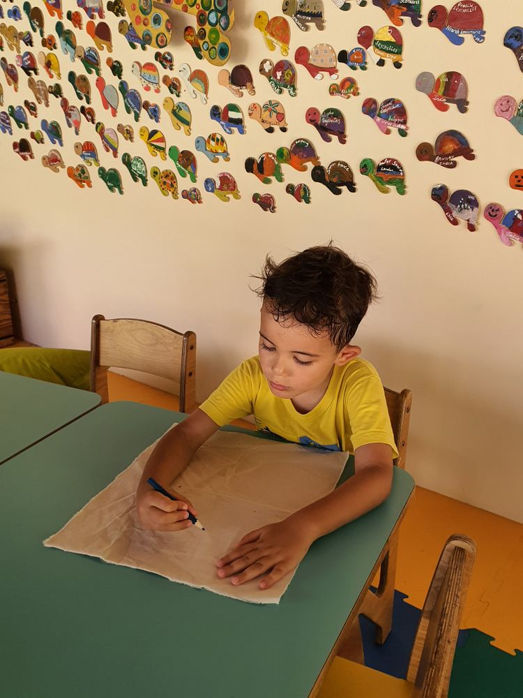 Copil desenând la o masă într-o cameră decorată.