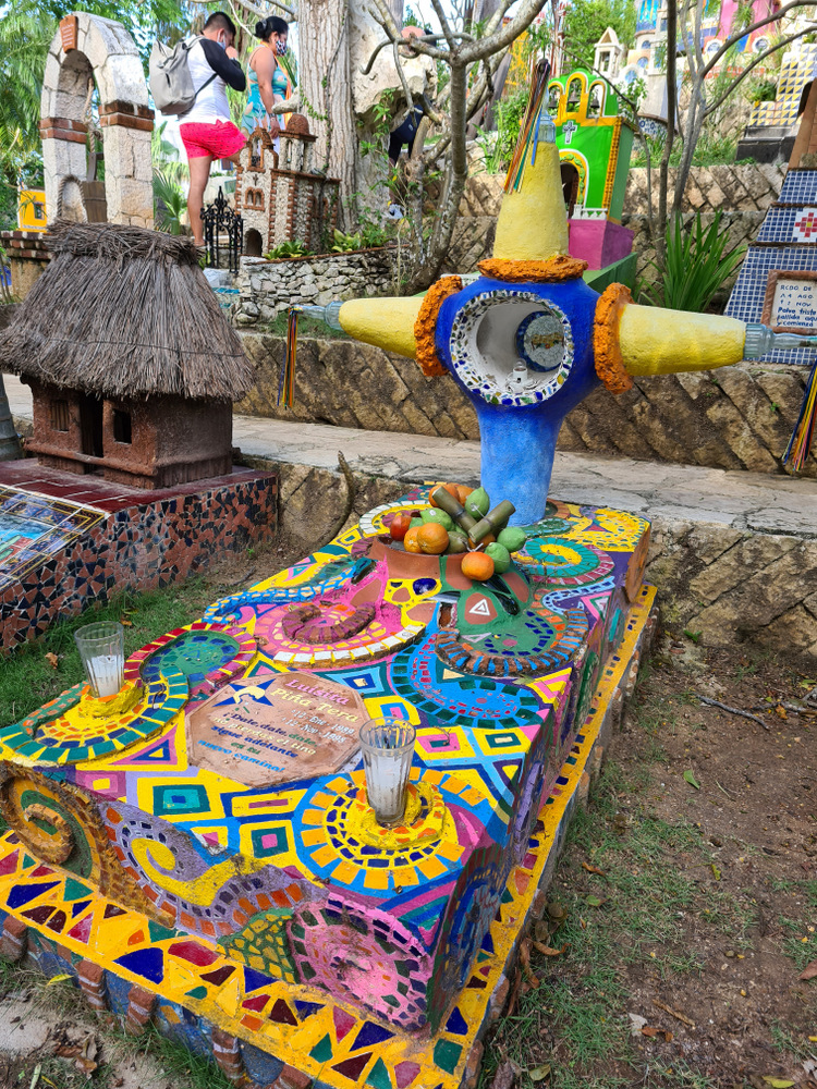 Construcție funerară multicoloră cu cruce, într-un spațiu decorat.