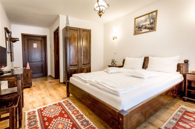 Dormitor cu pat dublu, mobilier din lemn și covor.