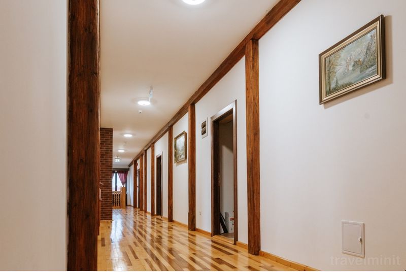 Coridor lung cu uși, tablouri și grinzi din lemn.