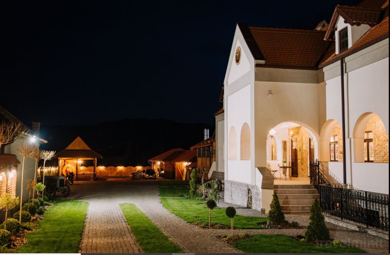 Intrare luminată într-o clădire albă, lângă o alee.