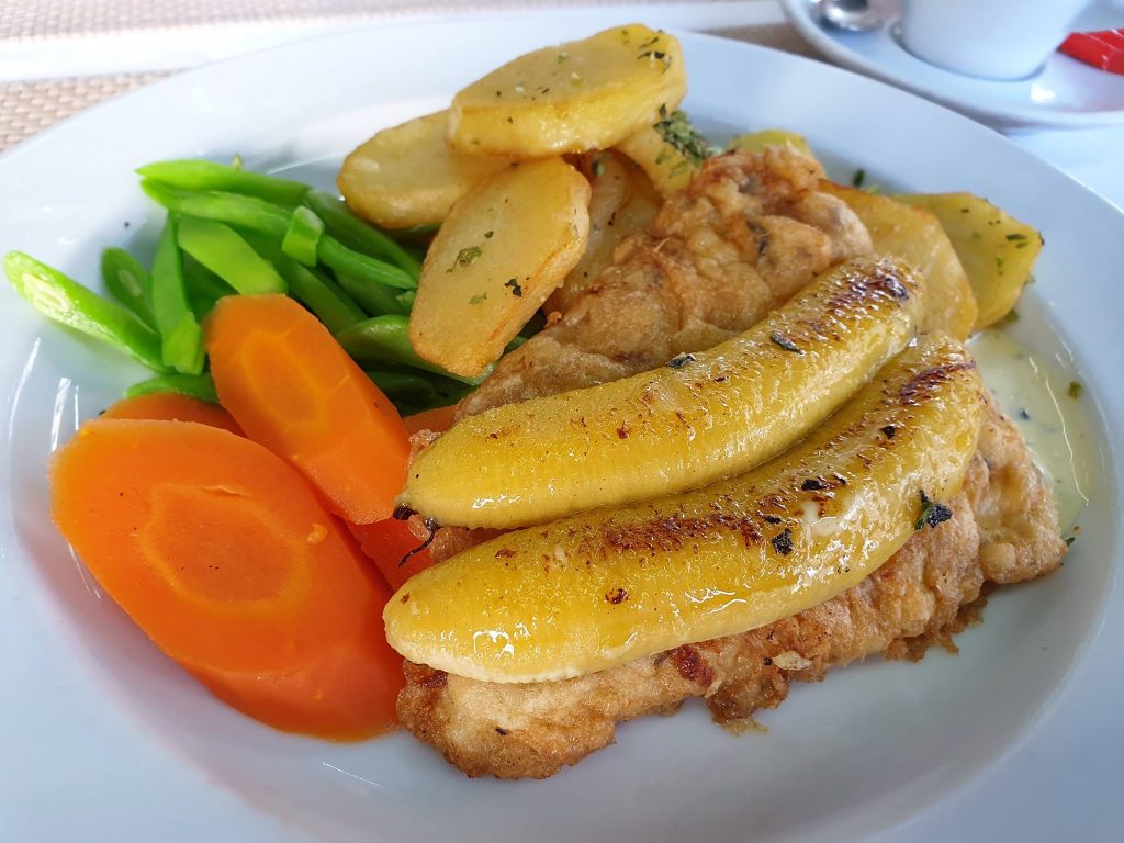 Preparat cu felii de banană, cartofi și legume colorate.