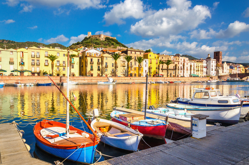 Bărci colorate într-un port cu clădiri reflectate în apă.