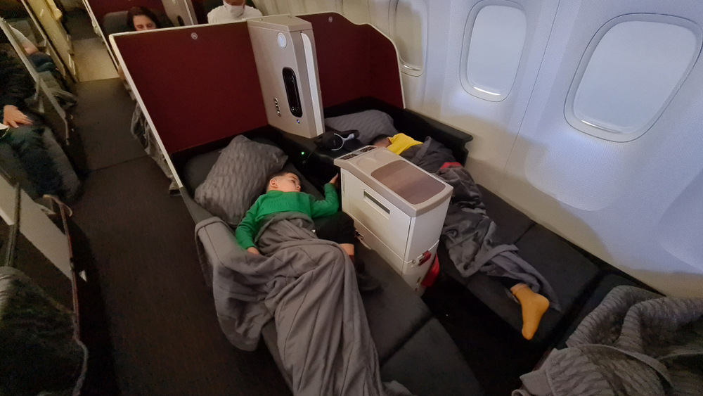 Copil întins sub pătură într-un fotoliu de avion.