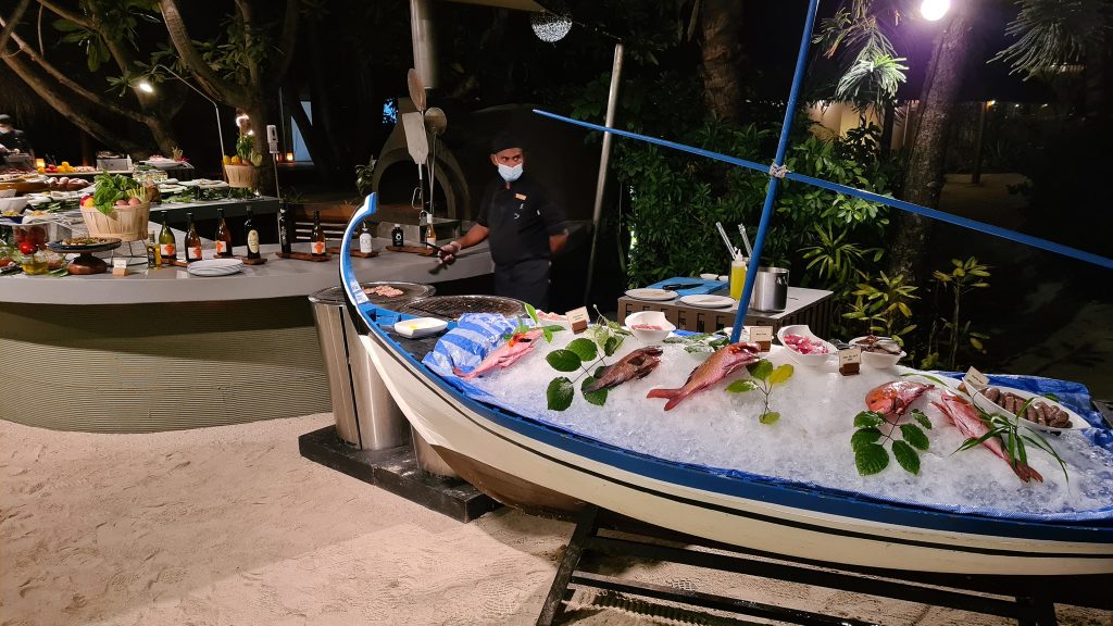 Pește și fructe de mare expuse într-o barcă decorativă.