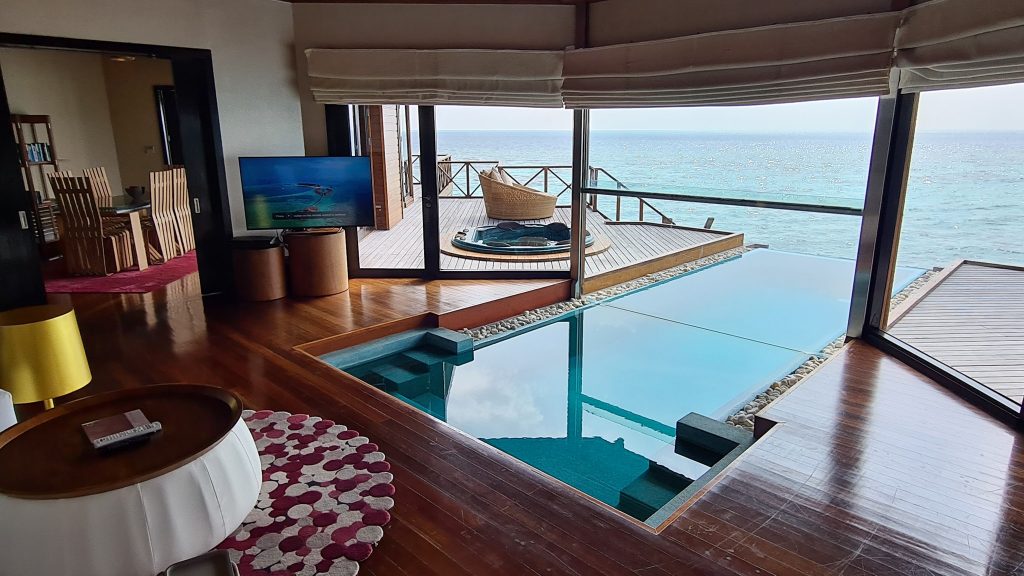 Interior deschis spre piscină și terasă deasupra mării.