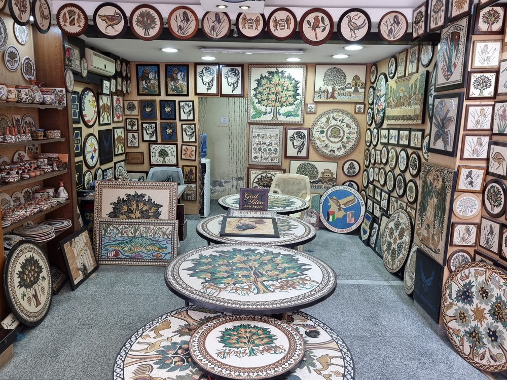 Încăpere plină cu mese, tablouri și obiecte decorate cu mozaic.