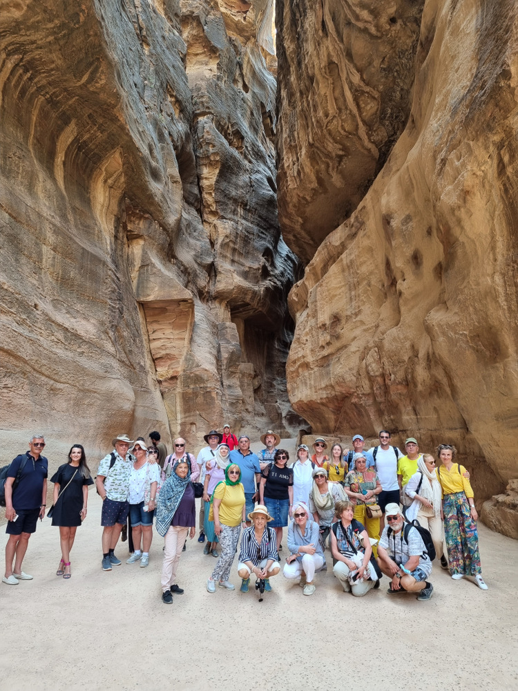 Grup de turiști pozând într-un defileu cu pereți înalți.