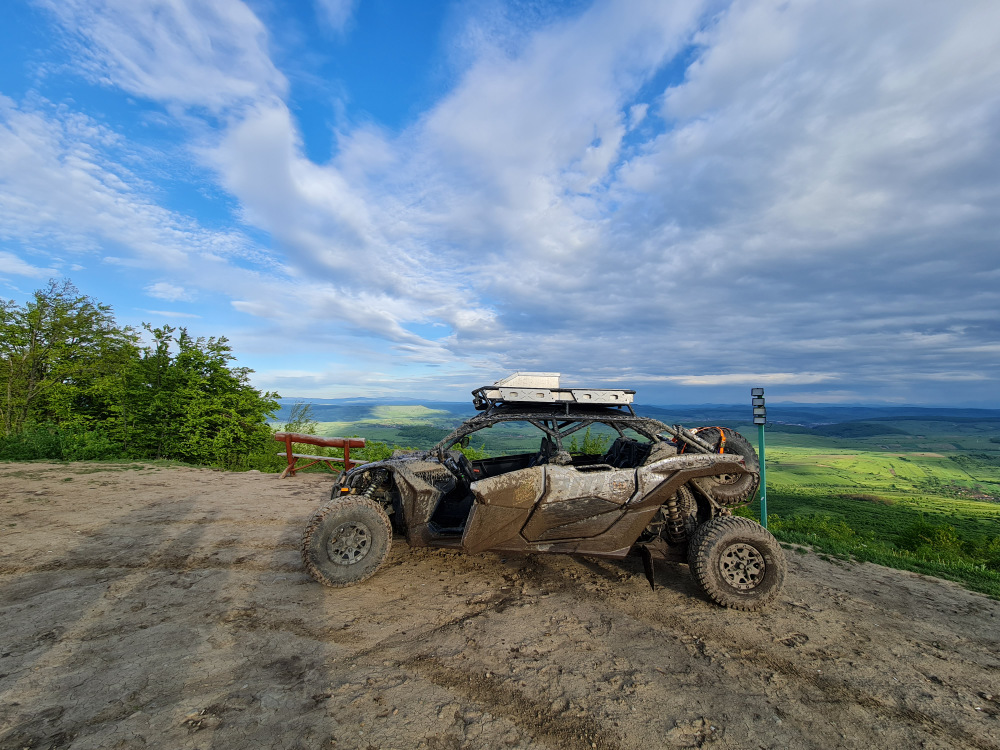 Vehicul de teren murdar parcat pe o culme panoramică.