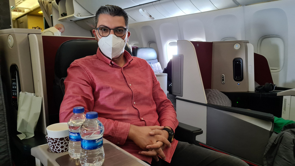 Bărbat cu mască așezat într-un fotoliu de avion.