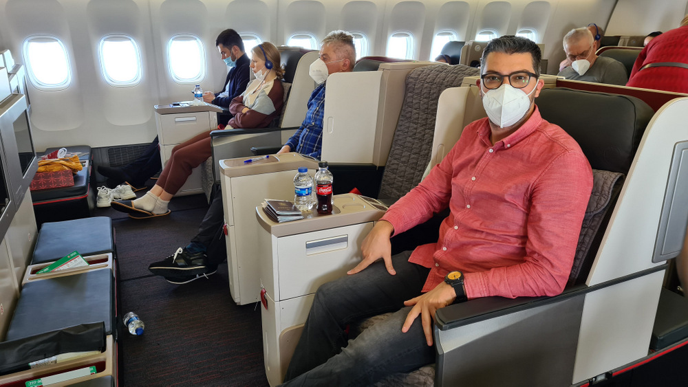 Bărbat cu mască așezat lângă măsuța din avion.