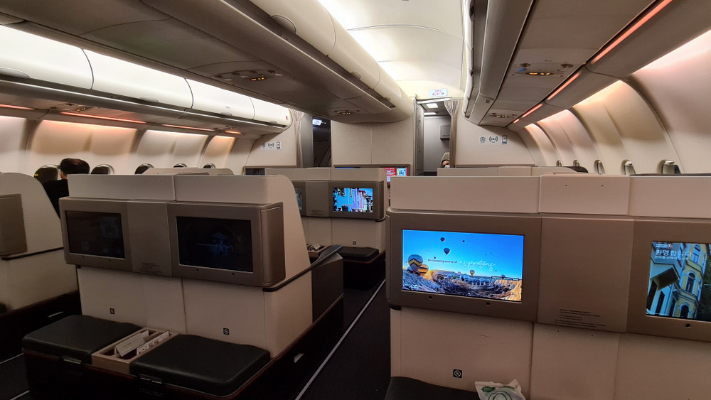 Rânduri de fotolii cu ecrane individuale în cabina avionului.
