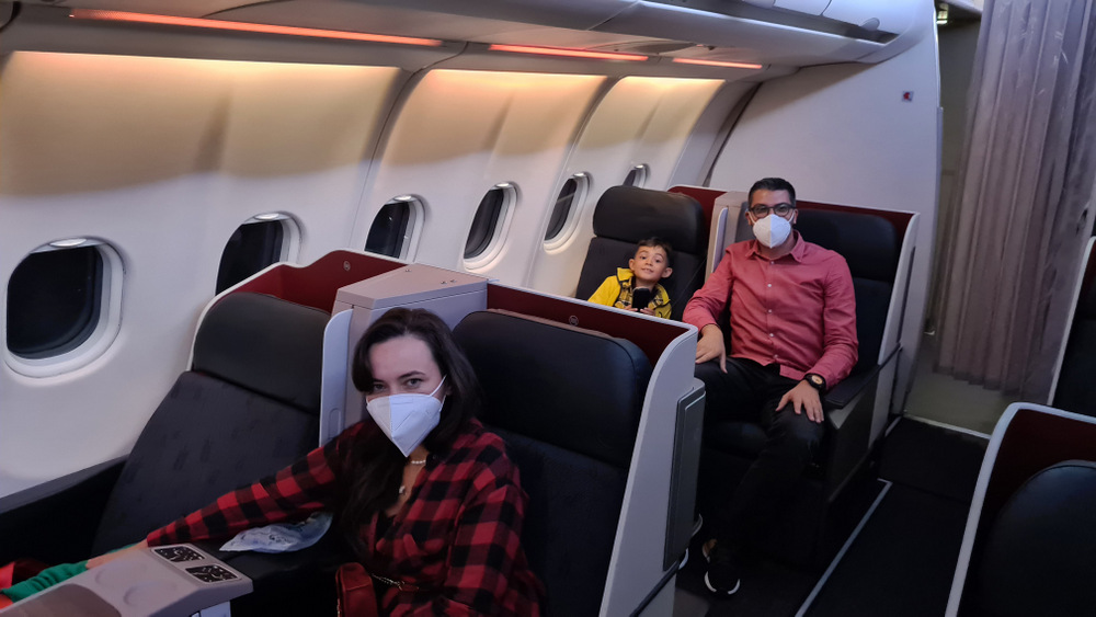Pasageri cu măști așezați în fotolii spațioase de avion.