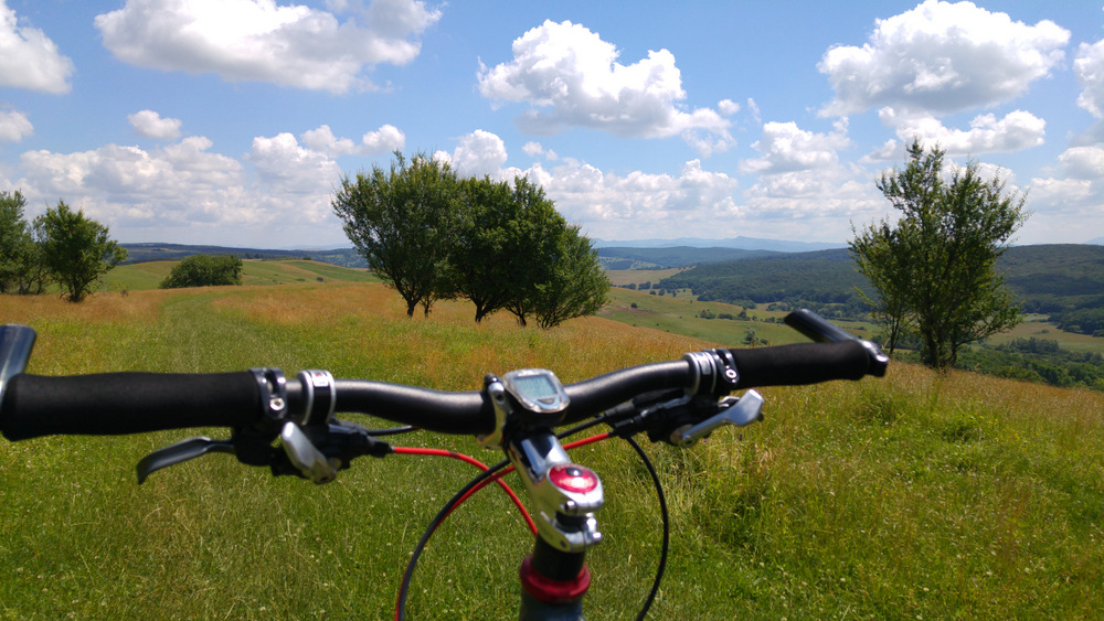 Ghidon de bicicletă în fața unui peisaj cu dealuri.