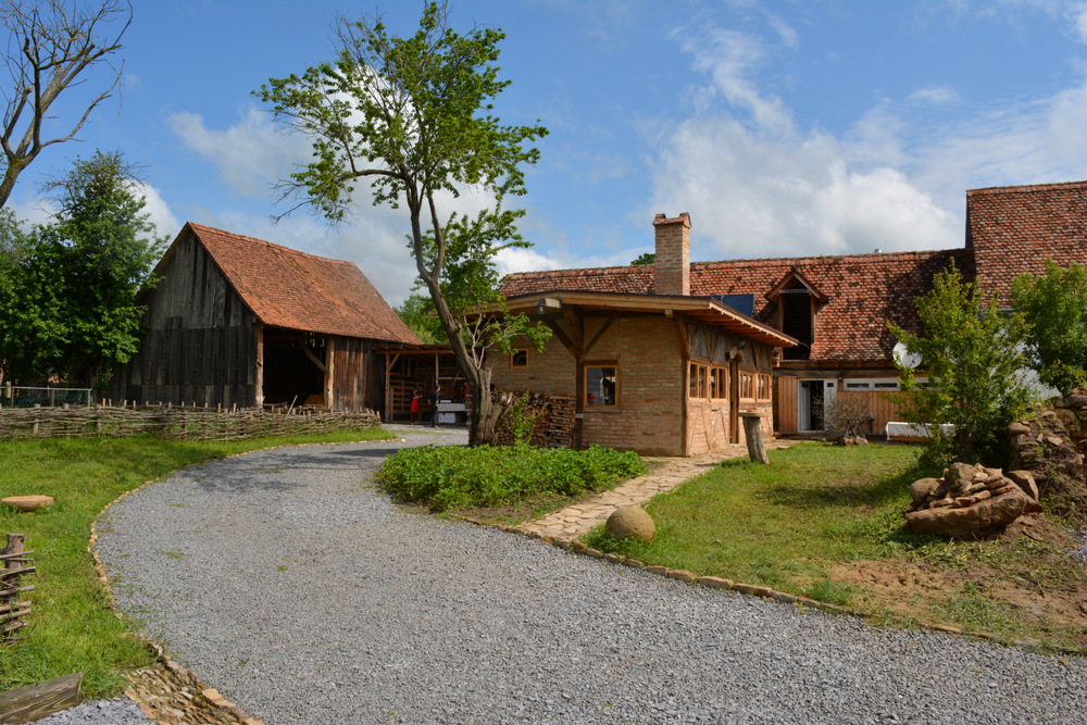 Curte rurală cu alee de pietriș și clădiri vechi.