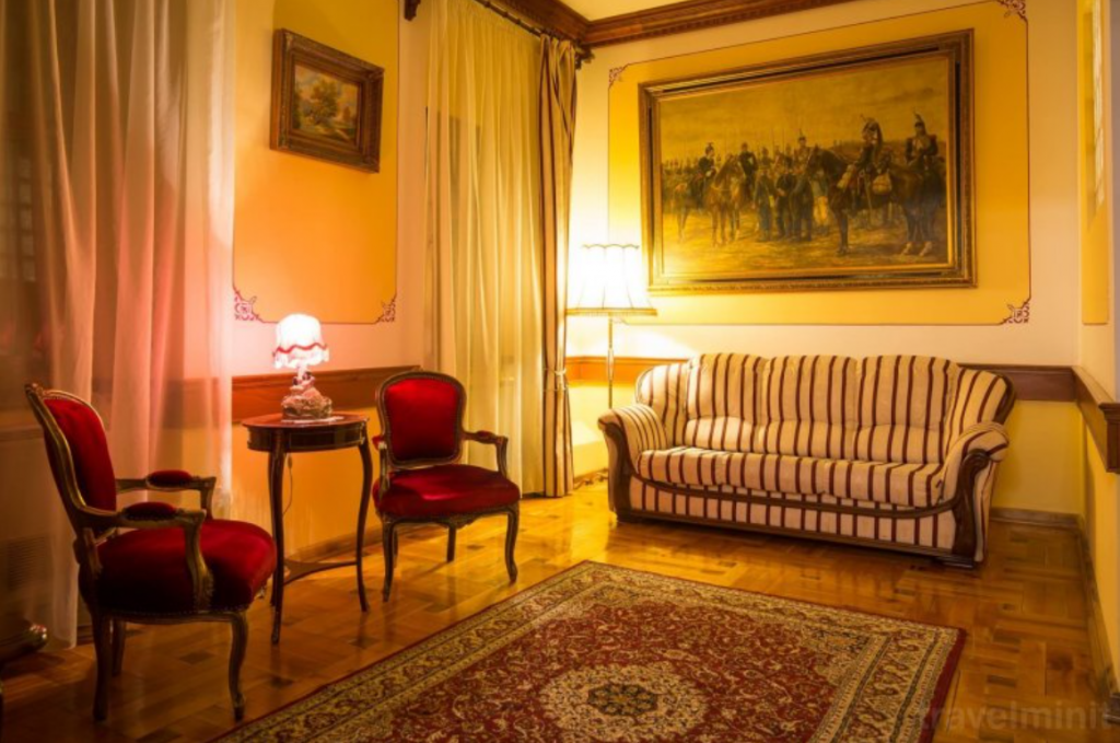 Salon cu canapea în dungi, fotolii și tablou mare.