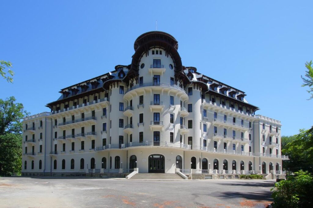 Clădire albă monumentală cu multe ferestre și acoperiș curbat.