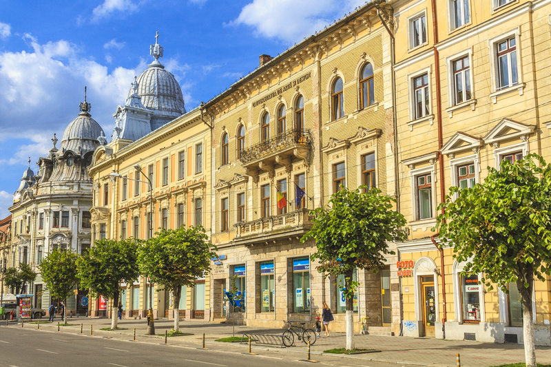 Clădiri istorice cu fațade galbene și cupole, de-a lungul unei străzi.