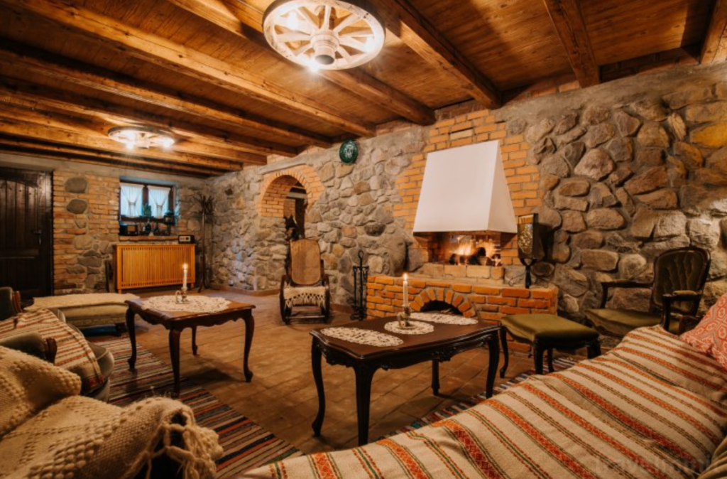 Living rustic cu pereți din piatră, canapele și mese din lemn.