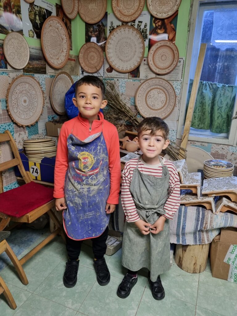 Doi copii într-un atelier cu farfurii ceramice expuse