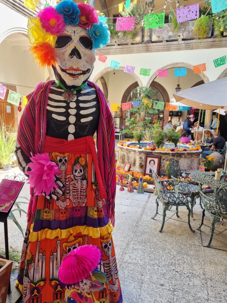Figură de schelet cu pălărie florală și îmbrăcăminte viu colorată.