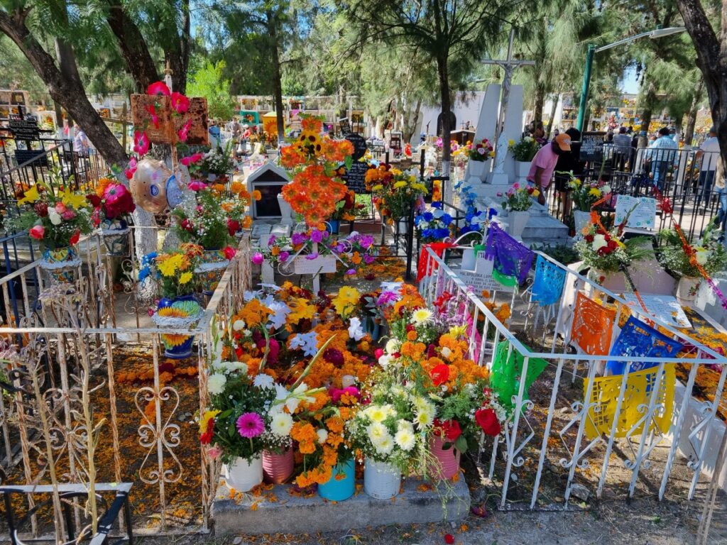 Morminte împodobite cu flori colorate și decorațiuni într-un cimitir.