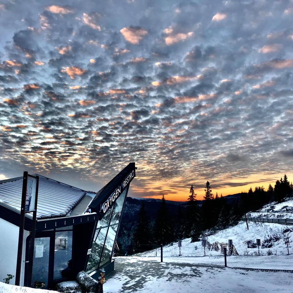Cabane lângă zăpadă sub cerul colorat al apusului