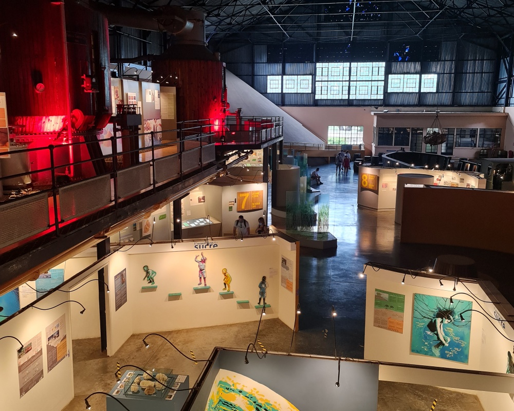 Interior de muzeu industrial, cu pasarele și exponate pe două niveluri.