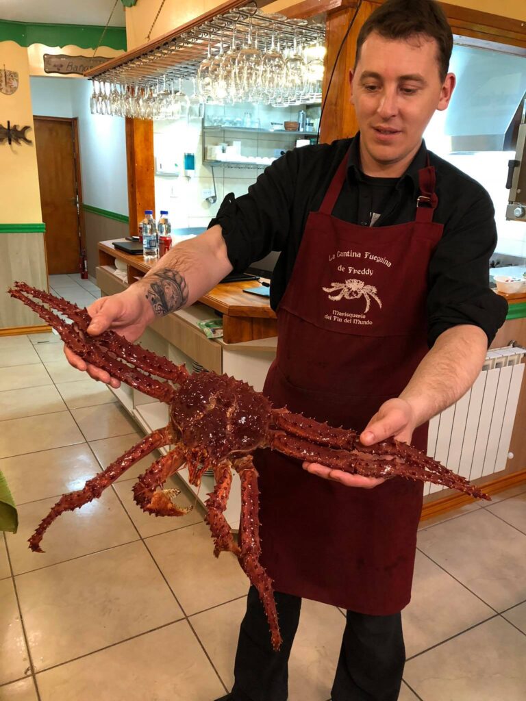 Angajat al unui restaurant ținând un crab mare în mâini.