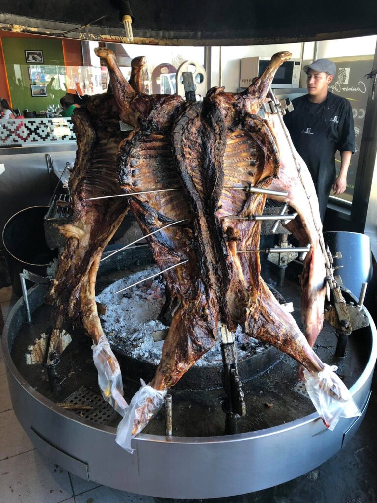 Bucăți de carne fixate vertical în jurul unui grătar circular.