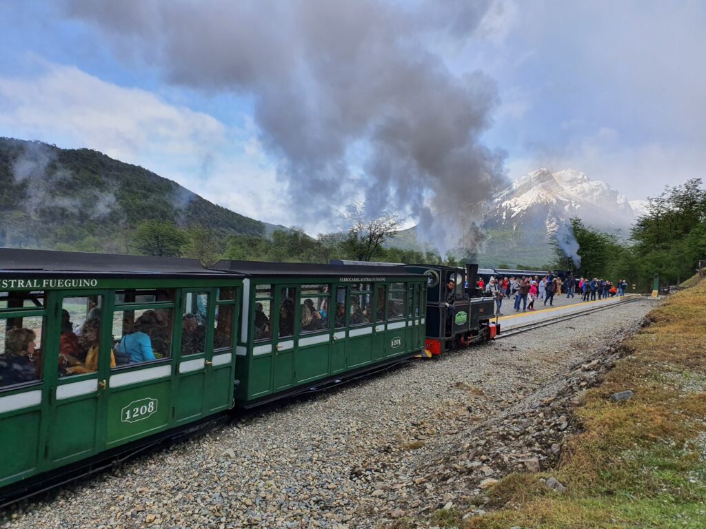 Tren cu vagoane verzi, într-un peisaj montan cu fum